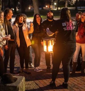 a group of people standing around a man holding a candle