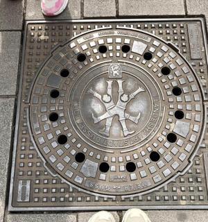 地上的金属井盖，周围站着一些人