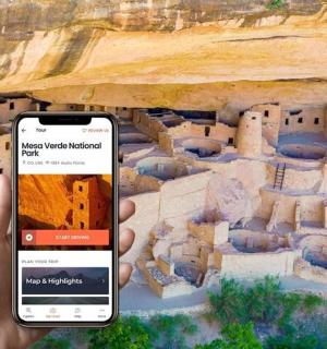 osoba držící mobilní telefon před hradem