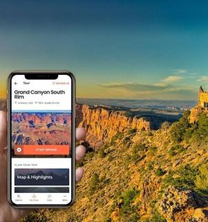 osoba držící mobilní telefon před hradem