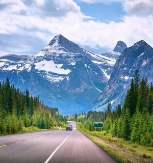 eine Straße mit einem Berg im Hintergrund mit einem Auto