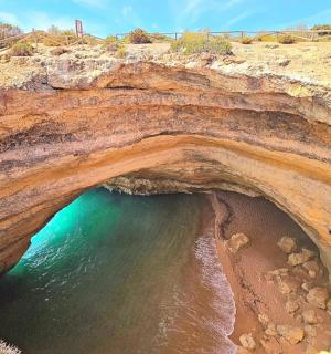 a large cave on a beach with the ocean