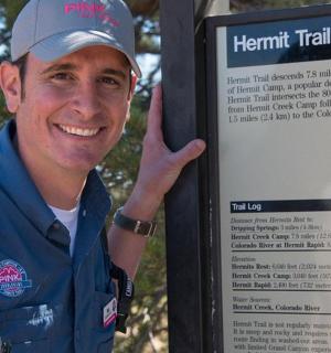 一名戴着帽子的男子站在标志牌旁边