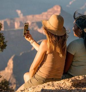 两名女子坐在岩石上拍摄大峡谷