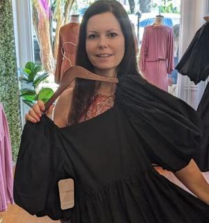 一名女子在服装店里拿着一件衣服