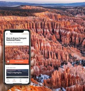 osoba držící mobilní telefon před kaňonem