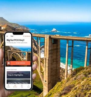 a person holding up a cell phone to take a picture of the ocean