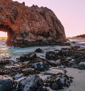 an arch in the rocks on a rocky beach