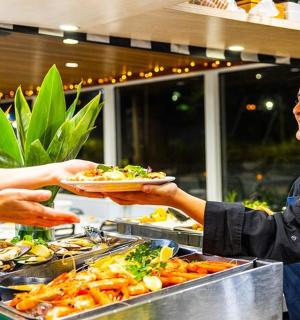 a woman handing a woman a plate of food