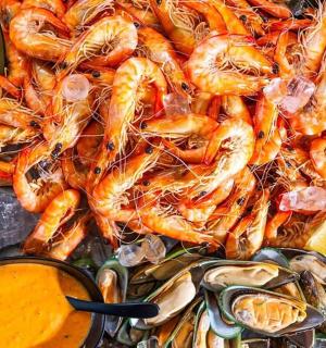 a tray of shrimp and other food withmons and dip