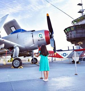 a young girl is looking at a plane on display