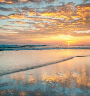 Západ slunce na pláži s odrazem ve vodě