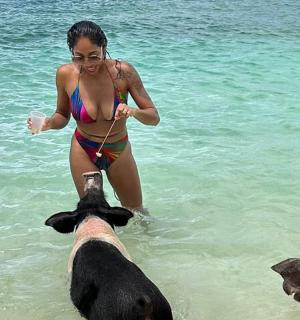 a woman in a bikini playing with a dog in the water