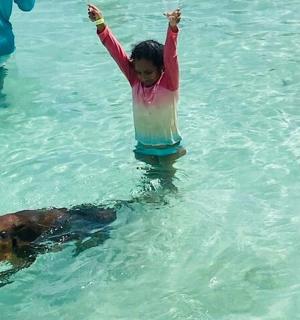 a little girl in the water with a dog
