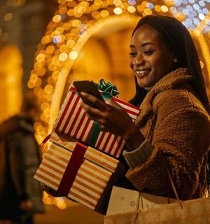 一位女士手里拿着圣诞礼物，看着手机