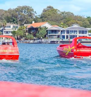 two red boats in the water near some houses
