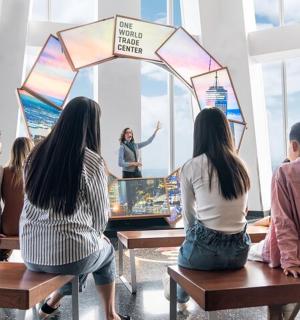 一群人坐在长椅上观看一名女子玩电子游戏