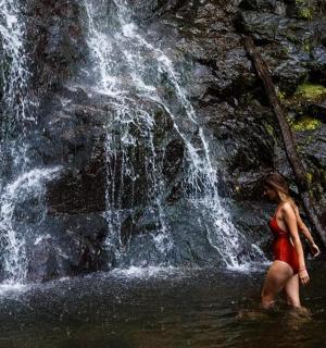 一名女子站在瀑布前的水中