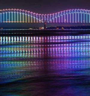 a large bridge with lights on the water at night