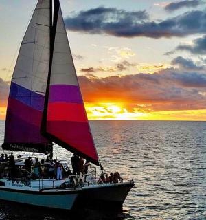 日落时分，一群人在水中的帆船上