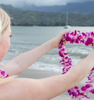 a woman holding a bunch of flowers on the beach