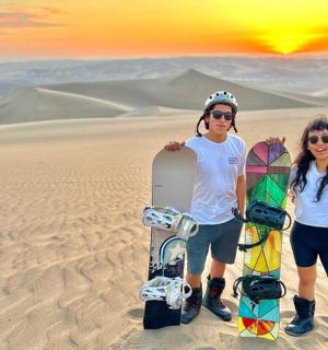 two people standing in the desert with snowboards