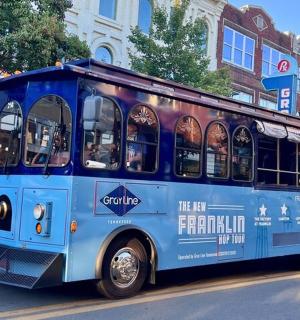 a blue trolley bus driving down a city street