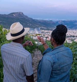 two people standing in a vineyard drinking white wine