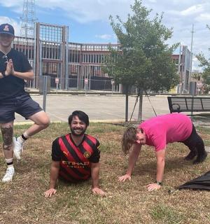 skupina lidí stojících v trávě poblíž sochy