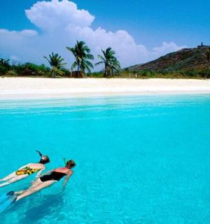 two women laying on surfboards in the water on a beach