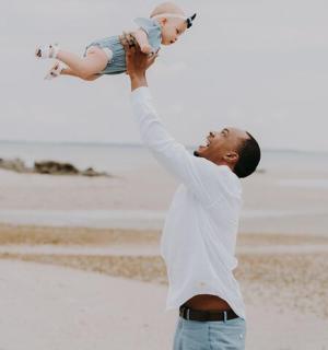 一名男子在海滩上抱着婴儿