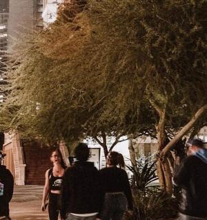 a group of people walking down a sidewalk at night
