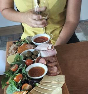 a person holding a glass of wine and a plate of food