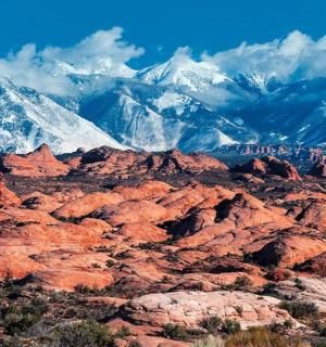 a view of the red rocks and snow covered mountains