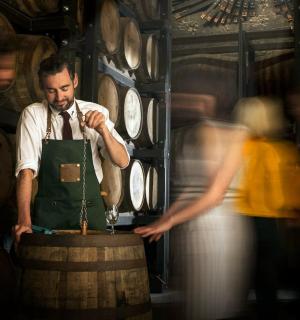 一名穿着围裙的男子站在桶旁边