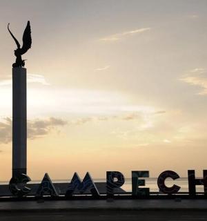 a statue of a bird on a pole next to the ocean