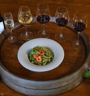 Una mesa de madera con un plato de comida y copas de vino.
