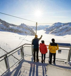 eine Gruppe von drei Personen steht auf einer Aussichtsplattform im Schnee
