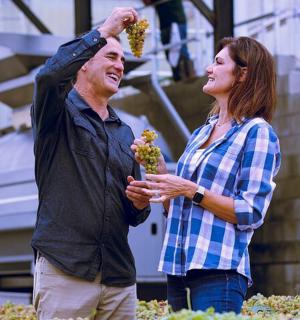 a man and a woman holding clusters of grapes