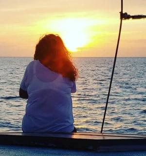 a woman sitting on a boat watching the sunset