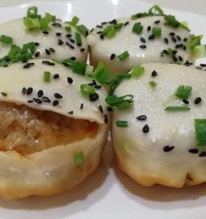 two donuts with white icing and green onions on a plate