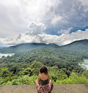 žena sedící na vrcholu skály a dívající se na jezero