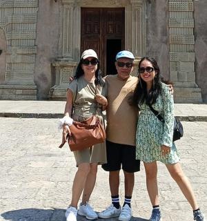 tři lidé pózují pro fotografii před budovou