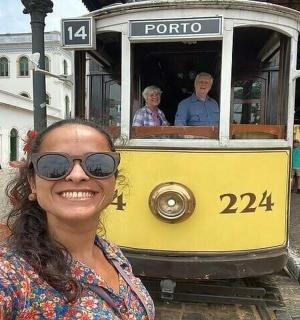 a woman standing in front of a yellow trolley car