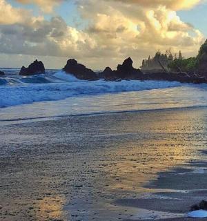 a beach with some waves and rocks in the water