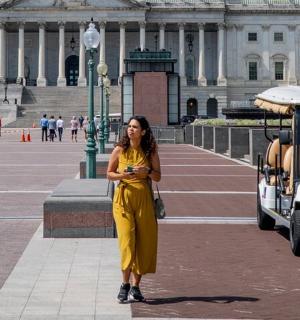 一位身穿黄色连衣裙的女士站在高尔夫球车旁