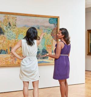 two women looking at a painting in a museum