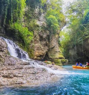 a group of people on a raft in a river with a waterfall