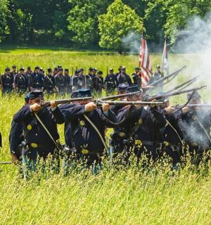 a group of men standing in a field holding guns