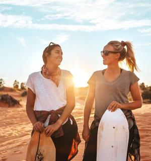 Dvě ženy stojí v písku se surfovými prkny